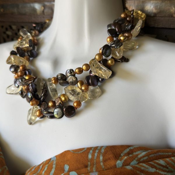 33. This necklace , designed by artist Barbara Wright is a Triple-stranded Quartz Crystal, Gold-Gilded Natural Pearls, and Mother of Pearl Necklace. It is a handmade piece of jewelry that exudes elegance and sophistication.