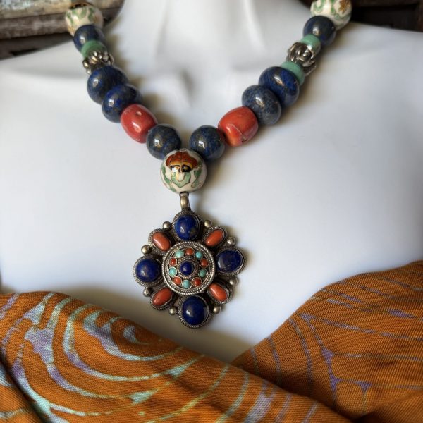 19. This Gorgeous Antique Nepalese Pendant Necklace designed by artist Barbara Wright of Dallas Texas features a stunning combination of authentic turquoise, coral, Afghan lapis Lazuli, Chinese porcelain, and 925 silver rose-shaped beads , creating a unique and eye-catching worldly accessory. The Asian-inspired design with a touch of orange and blue main stones adds a vibrant, contrasting touch. Made with 925 silver purity and ethically sourced from Nepal, this pendant exudes quality craftsmanship and a sense of intrigue. Perfect for those who appreciate artisanal jewelry with a blend of traditional and contemporary style.
