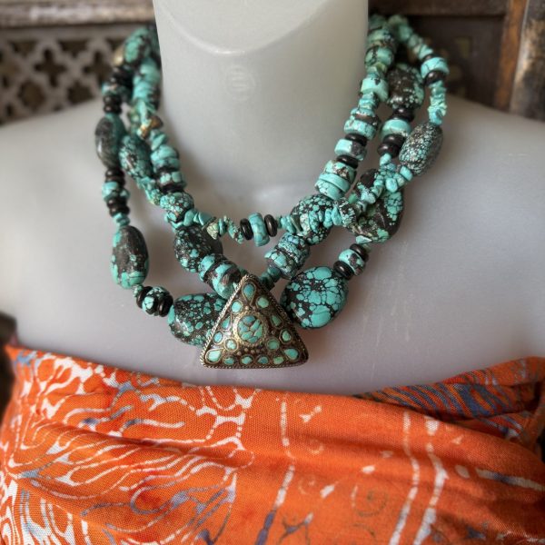 26. This product is a stunning turquoise and 925 silver detailed, triangular pendant and beaded necklace by artist Barbara Wright of Dallas, Texas. The pendant features beautifully designed turquoise surrounded by Sterling Silver. The necklace showcases a Native American style with blue turquoise beads, adding a unique and colorful touch to the design. Made in the United States, this piece of jewelry harmoniously combines quality craftsmanship with traditional motifs, making it a standout accessory for any outfit. Each bead is double knotted by hand!