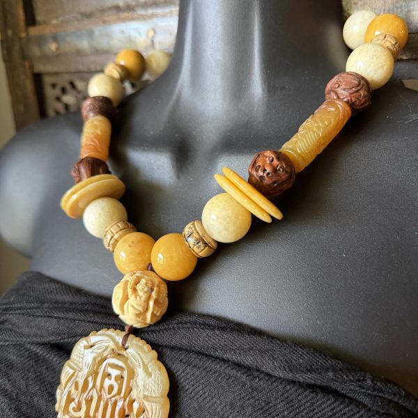 10. This stunning carved jade pendent and beaded , Jasper, wood, and jade necklace features intricate jade and wooden carvings and a beautiful multi-color design made of authentic jade, wood and Jasper beads ranging from cream, brown to golden yellows. The antique original materials were crafted in China artisans but designed by artist Barbara Wright of Dallas, TX. The necklace is 19.5 inches in length. This necklace is a stunning piece of artisan jewelry that is one of a kind and each bead is double-knotted by hand on silk thread.