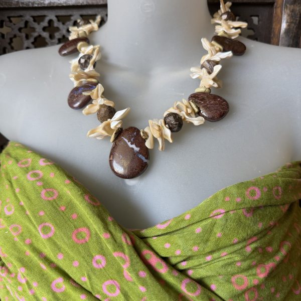 The Australian Brown Boulder Opal and Mother of Pearl Beaded Pendant Necklace by artist Barbara Wright of Dallas, TX is a handcrafted piece of artisan jewelry that showcases a beautiful pendant design throughout. The main stone, brown, iridescent Boulder Opals have been ethically sourced from Australia. You will see the pendants complemented by a secondary stone of Mother of Pearl nuggets , and beautifully sparkling, faceted boulder opals creating a unique and luxurious look. This necklace embodies the beauty and elegance of natural stones, making it a stunning accessory for any jewelry lover. Each bead is double-knotted by hand!
