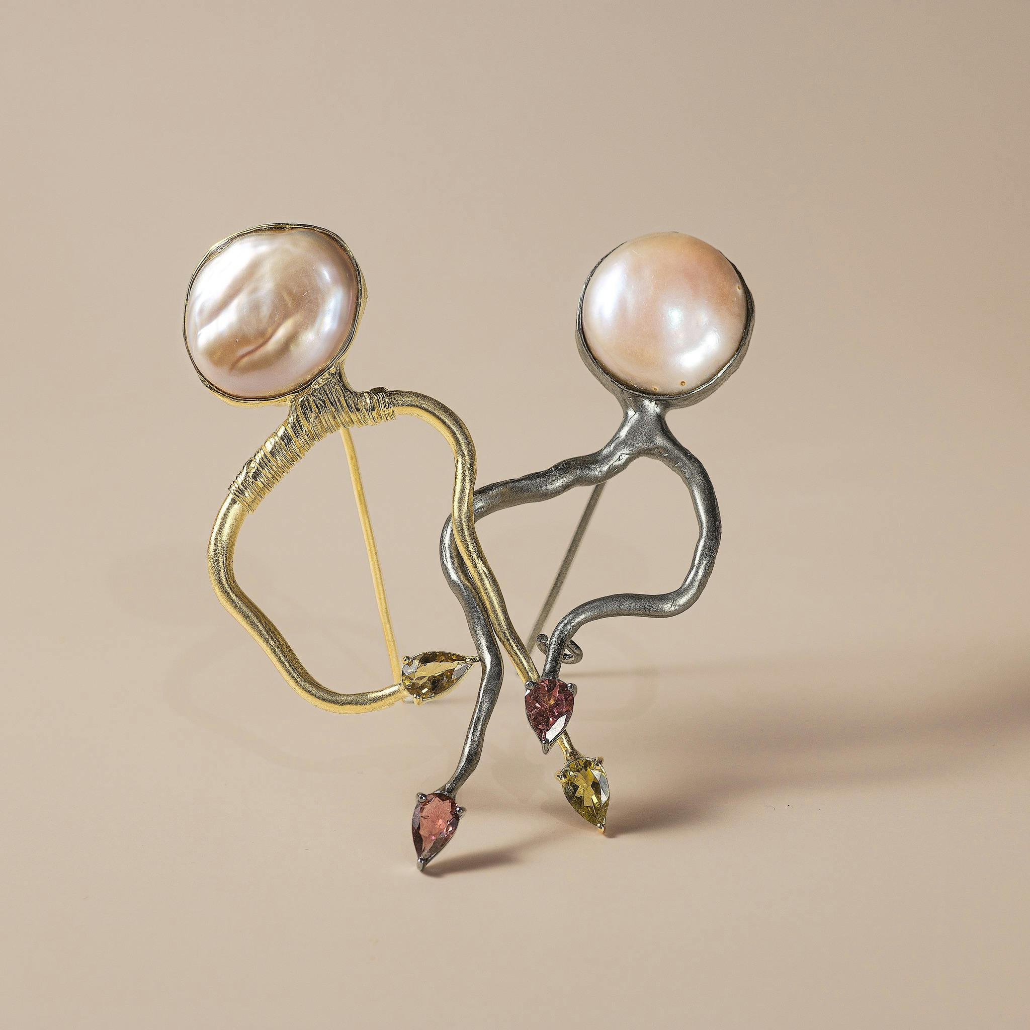 Creative close-up of artistic pearl and metal jewelry with a brown backdrop, showcasing intricate design and elegance.